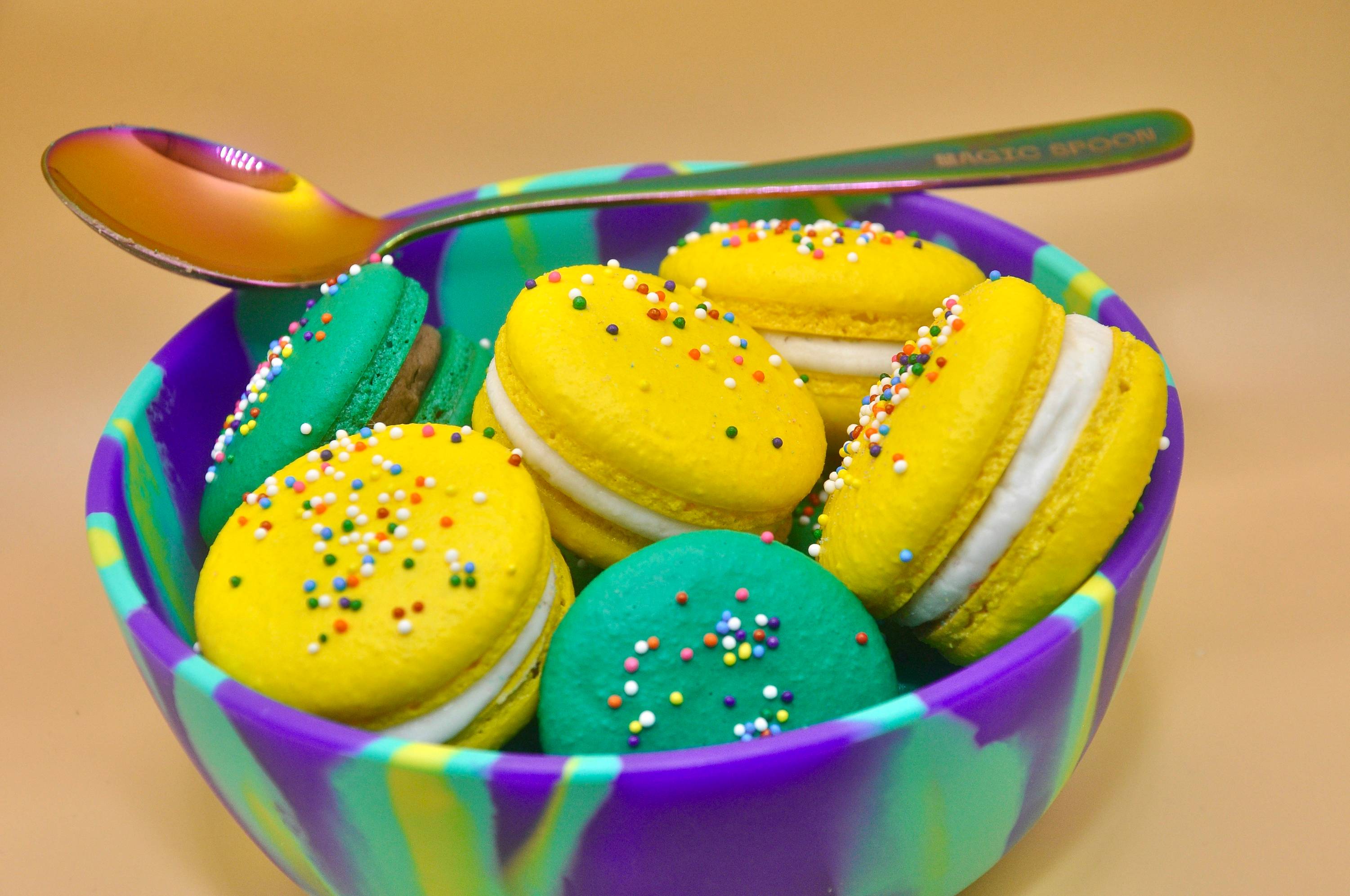 a blue bowl filled with yellow and green macaroons
