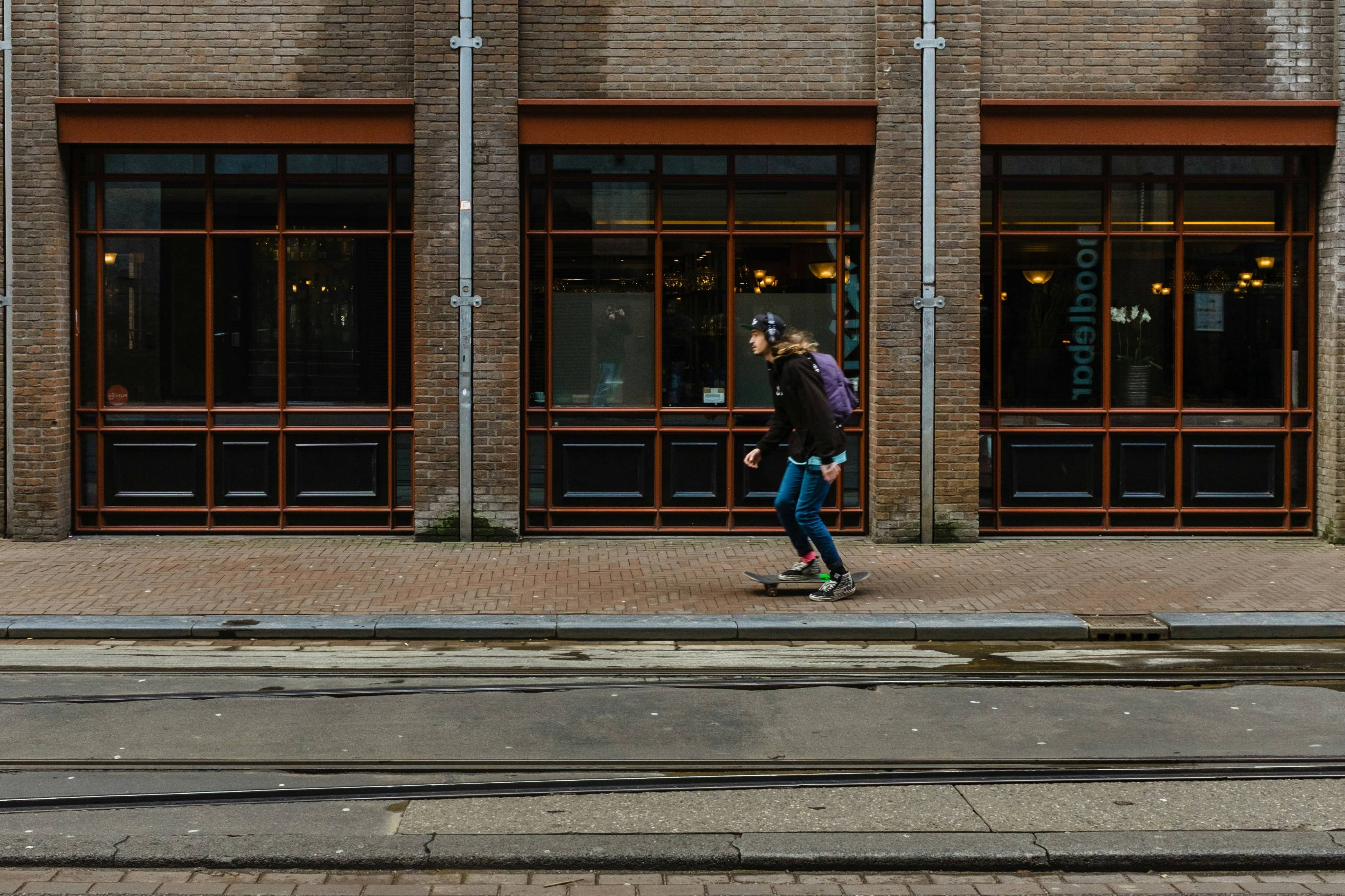 man skateboard on brown pavement beside building